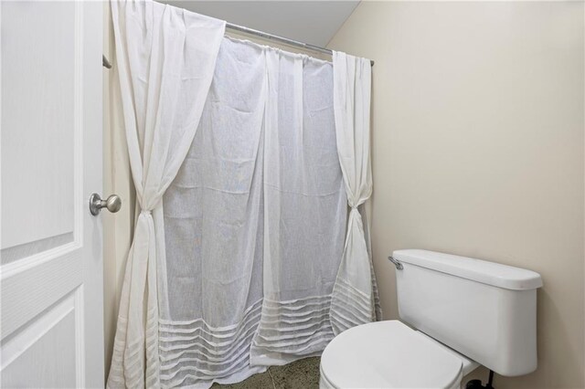 bathroom featuring a shower with shower curtain and toilet