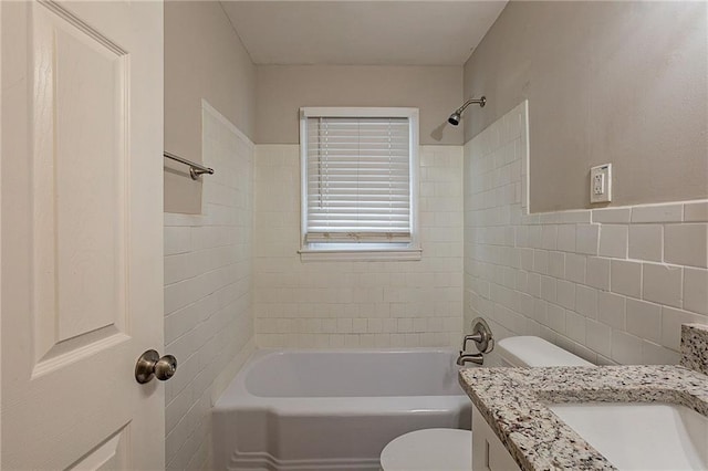 full bathroom with tiled shower / bath, vanity, tile walls, and toilet