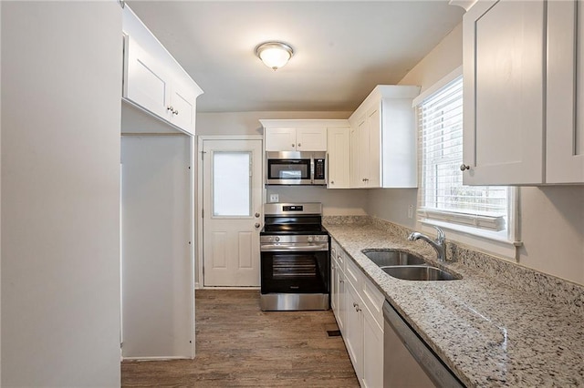 kitchen featuring white cabinets, sink, light stone countertops, a healthy amount of sunlight, and stainless steel appliances