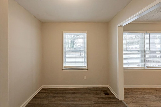 spare room with plenty of natural light and dark hardwood / wood-style floors