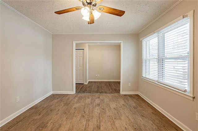 empty room featuring a textured ceiling, hardwood / wood-style flooring, ceiling fan, and ornamental molding