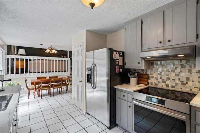 4255 Hidden Meadow Cir, Sugar Hill, GA 30518 - kitchen with appliances with stainless steel finishes, under cabinet range hood, gray cabinetry, tasteful backsplash, and a textured ceiling