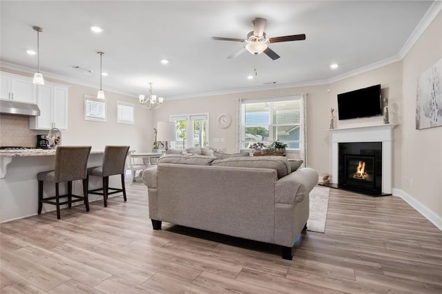 living room with light hardwood / wood-style floors, crown molding, and ceiling fan with notable chandelier