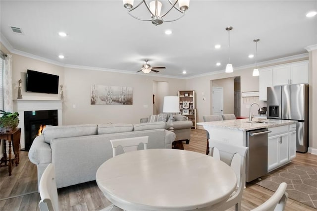 dining room featuring hardwood / wood-style floors, ornamental molding, sink, and ceiling fan with notable chandelier