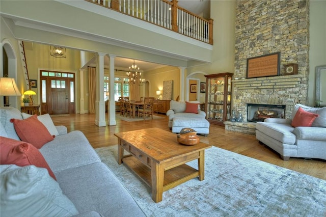 living room with an inviting chandelier, a fireplace, light hardwood / wood-style floors, and a high ceiling