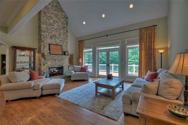 living room with a stone fireplace, hardwood / wood-style floors, high vaulted ceiling, and french doors