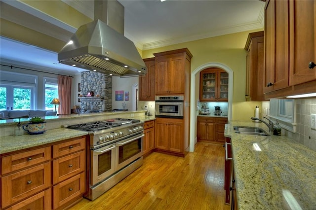 kitchen with sink, stainless steel appliances, light stone countertops, and island exhaust hood