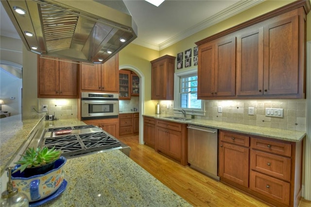 kitchen featuring sink, light stone counters, island range hood, stainless steel appliances, and light hardwood / wood-style floors