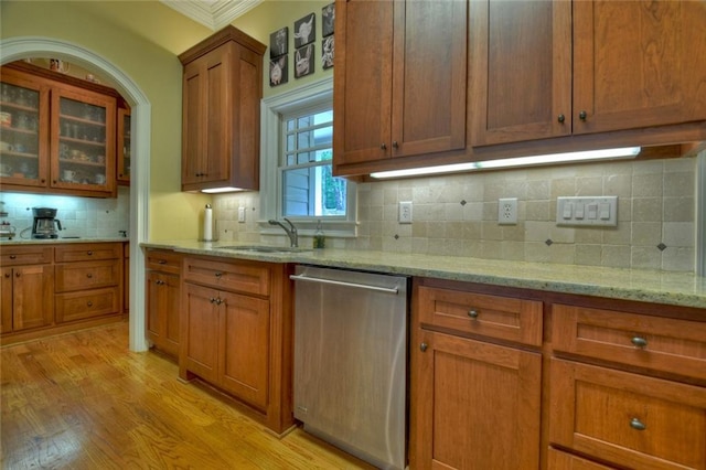 kitchen featuring light stone counters, stainless steel dishwasher, sink, and backsplash