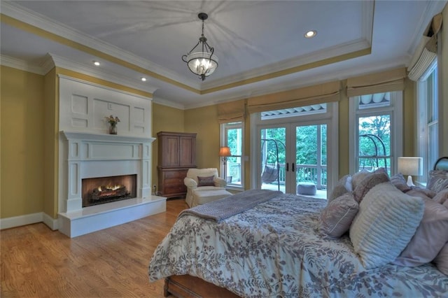 bedroom featuring hardwood / wood-style floors, ornamental molding, access to outside, a raised ceiling, and french doors