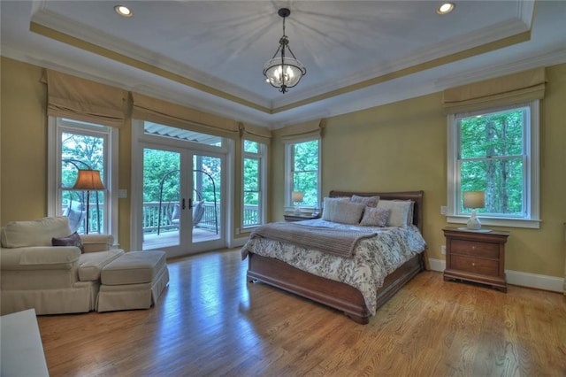 bedroom with french doors, a tray ceiling, light hardwood / wood-style floors, and access to exterior