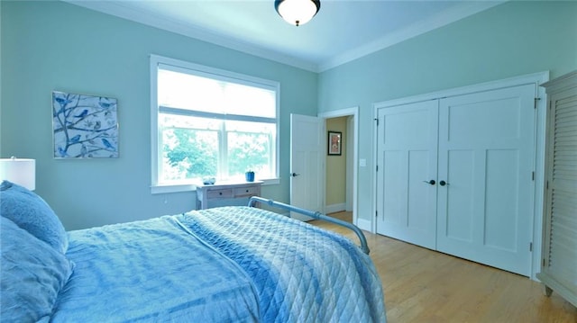 bedroom with light hardwood / wood-style flooring, ornamental molding, and a closet