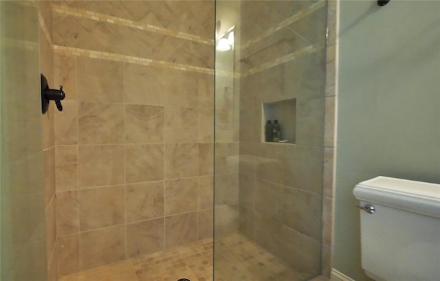 bathroom featuring a tile shower and toilet