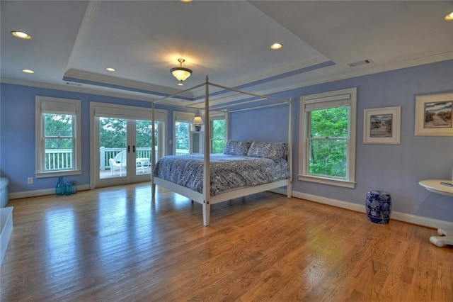 unfurnished bedroom with a raised ceiling, crown molding, hardwood / wood-style flooring, and french doors