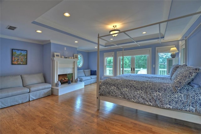 bedroom with french doors, crown molding, wood-type flooring, and a tray ceiling