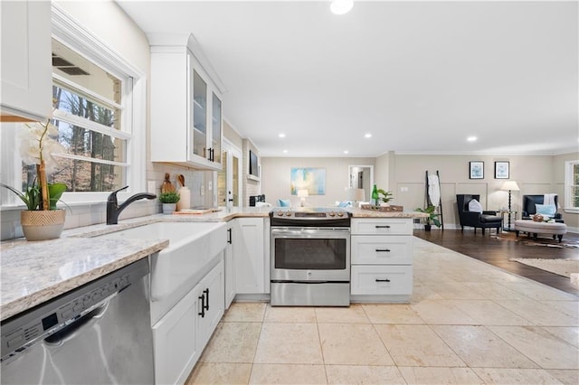 kitchen with appliances with stainless steel finishes, tasteful backsplash, light stone countertops, white cabinets, and light tile patterned flooring