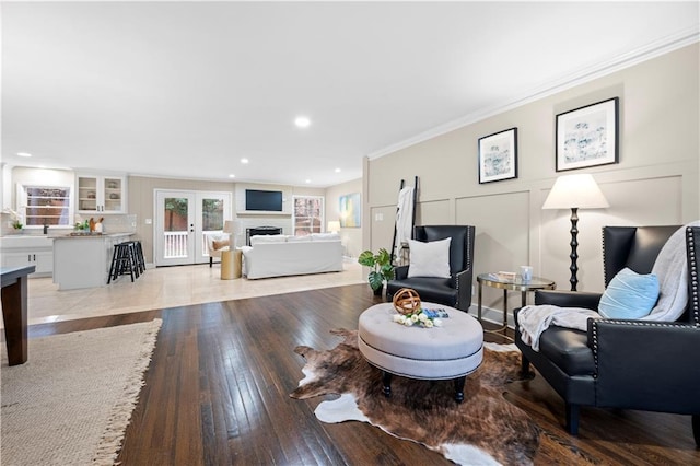 living room with crown molding, light wood-type flooring, and french doors