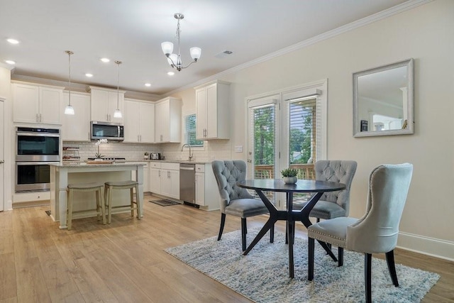 dining area with visible vents, baseboards, light wood-style floors, and ornamental molding