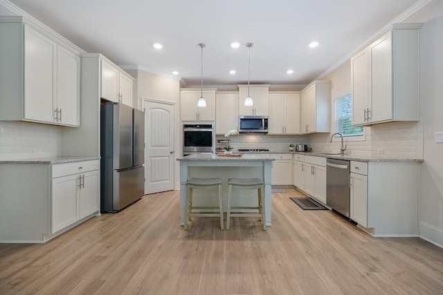 kitchen featuring appliances with stainless steel finishes, a kitchen island, light wood-type flooring, and a sink