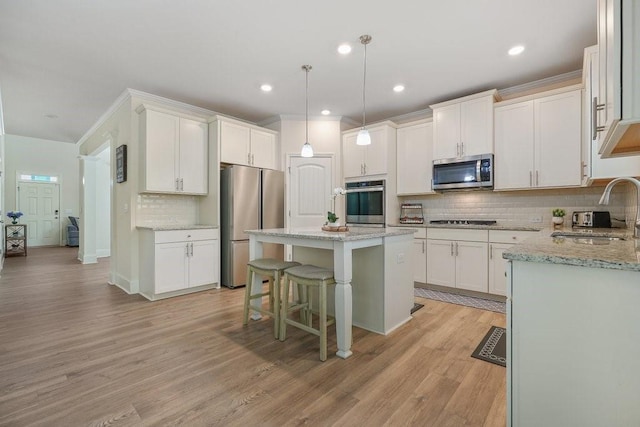 kitchen featuring a sink, light wood-style floors, appliances with stainless steel finishes, white cabinetry, and a center island