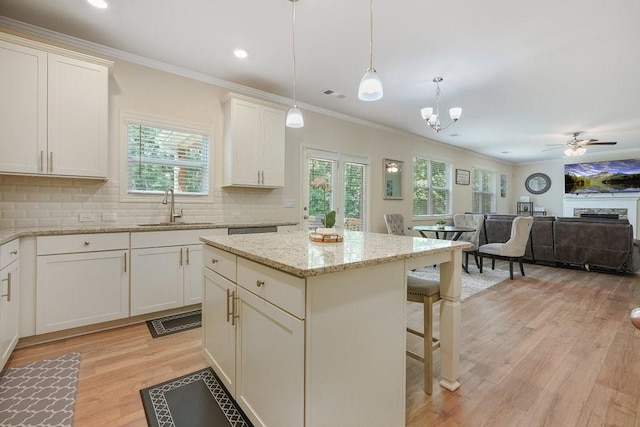 kitchen with tasteful backsplash, open floor plan, a breakfast bar area, light wood-type flooring, and a sink