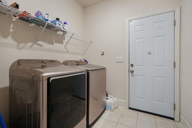 laundry room with laundry area, light tile patterned flooring, baseboards, and washer and clothes dryer