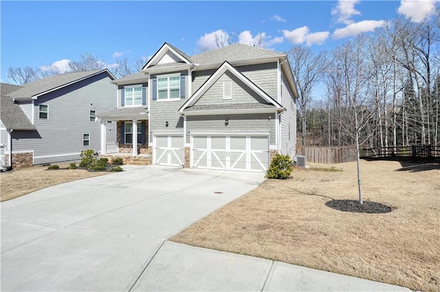 view of front of property with concrete driveway, central air condition unit, an attached garage, and fence