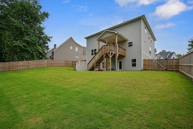 rear view of property with a yard, a deck, a fenced backyard, and stairs