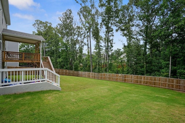 view of yard with a wooden deck, a fenced backyard, and stairs