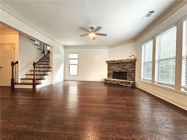 unfurnished living room featuring dark wood-type flooring, ceiling fan, a stone fireplace, and ornamental molding