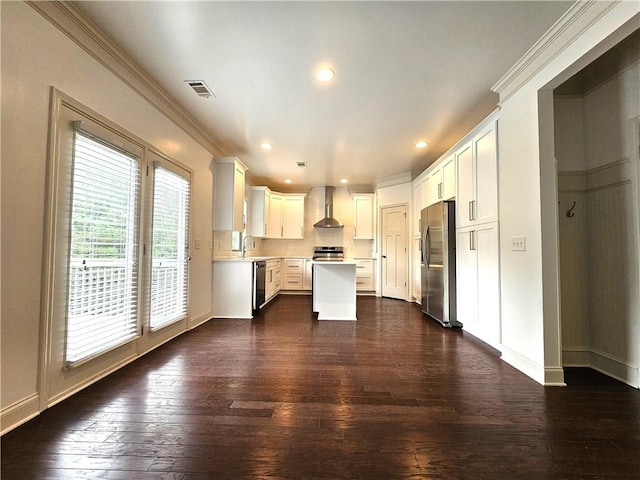 kitchen featuring dark hardwood / wood-style floors, wall chimney exhaust hood, stainless steel appliances, a center island, and white cabinets