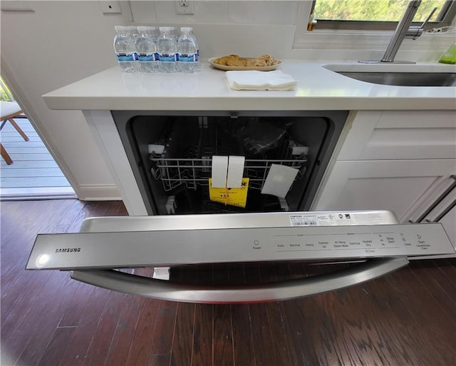 details featuring white cabinets, dishwasher, sink, and dark hardwood / wood-style flooring