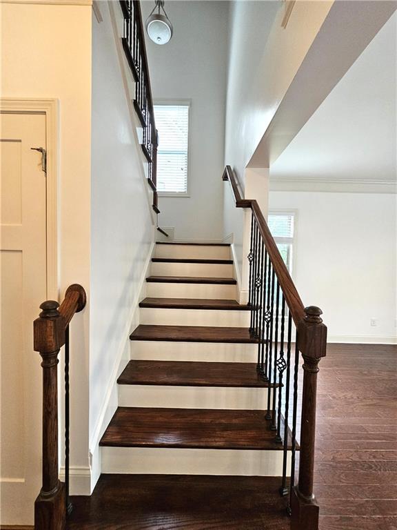 stairway with ornamental molding and hardwood / wood-style floors