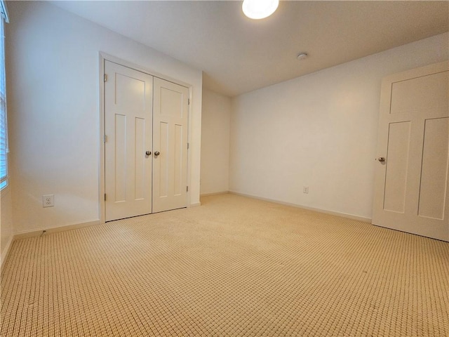 unfurnished bedroom with light colored carpet and a closet