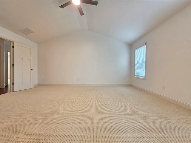 spare room featuring ceiling fan, light colored carpet, and vaulted ceiling