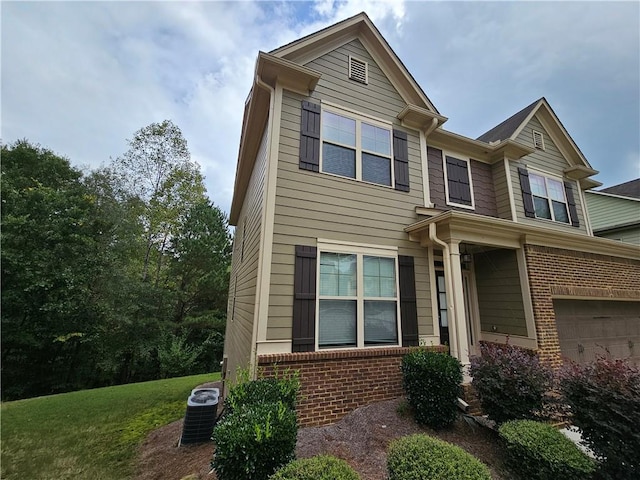 view of front of home with a front yard, central AC, and a garage