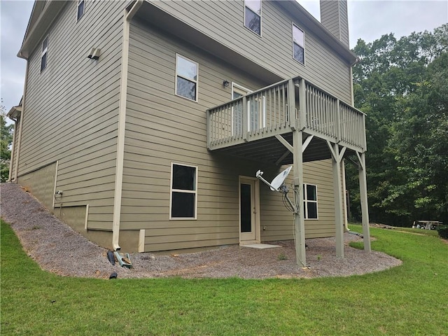 rear view of property featuring a balcony and a yard