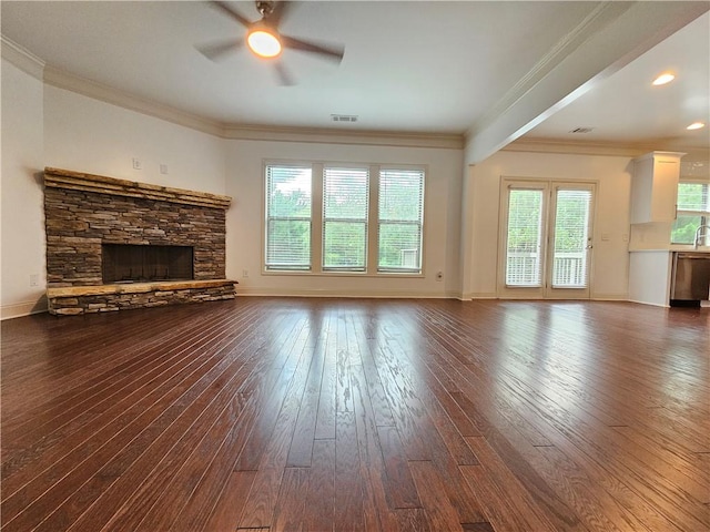 unfurnished living room featuring ornamental molding, a stone fireplace, hardwood / wood-style flooring, and plenty of natural light