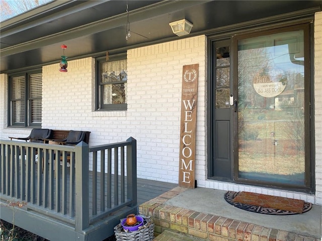 view of exterior entry with covered porch and brick siding