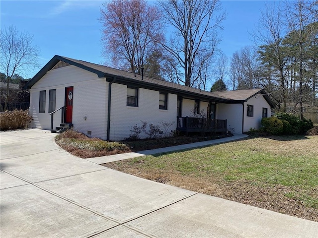 view of side of property with entry steps, crawl space, brick siding, and a yard