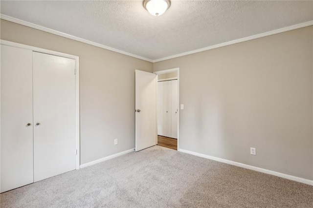 unfurnished bedroom featuring carpet, a textured ceiling, crown molding, and a closet