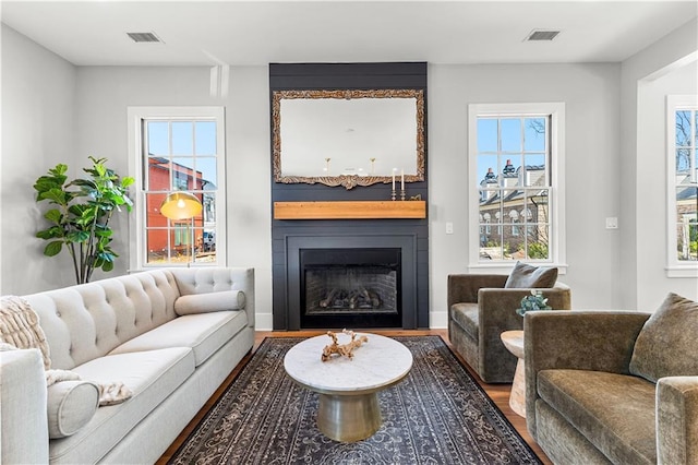 living room with visible vents, a large fireplace, and wood finished floors