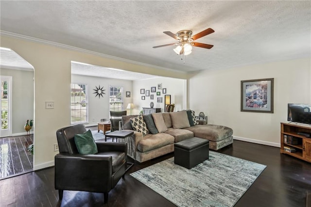 living room featuring baseboards, arched walkways, a textured ceiling, and dark wood finished floors