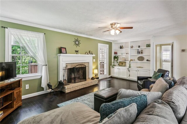 living room with crown molding, plenty of natural light, a fireplace, and a ceiling fan