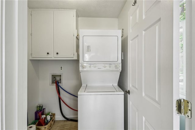 laundry room with stacked washing maching and dryer, baseboards, and cabinet space