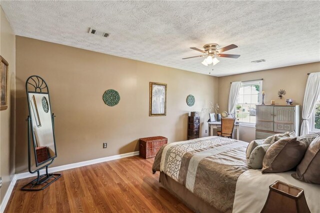 bedroom with a textured ceiling, visible vents, and wood finished floors