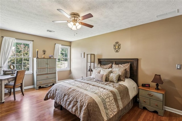 bedroom with baseboards, a textured ceiling, and visible vents