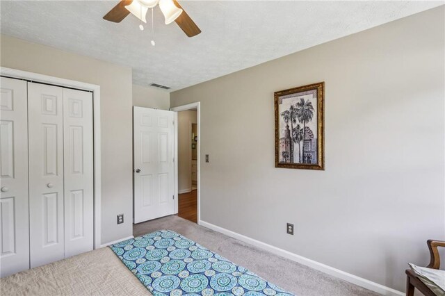 bedroom with a ceiling fan, visible vents, carpet floors, baseboards, and a closet