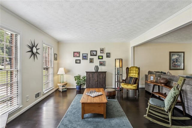 living area featuring a textured ceiling, baseboards, dark wood-type flooring, visible vents, and ornamental molding