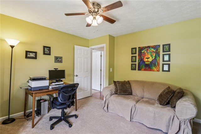 carpeted office space featuring baseboards and ceiling fan